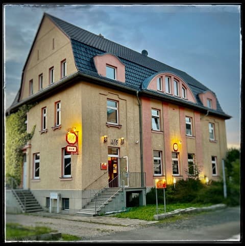 Das Haus Schlachthofstraße 31 in der Abenddämmerung, die Fenster der Bar sind erleuchtet.
